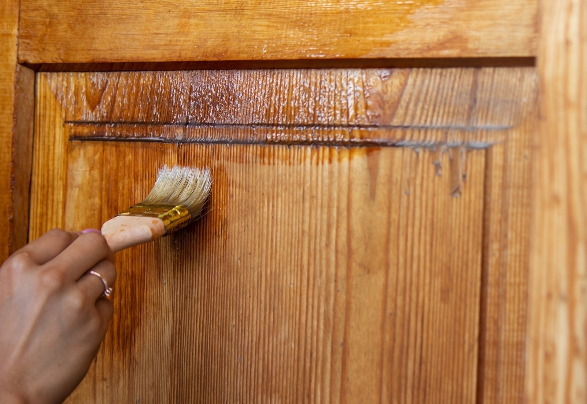 Beautiful young girl paints a wooden door. Summer work in the garden.