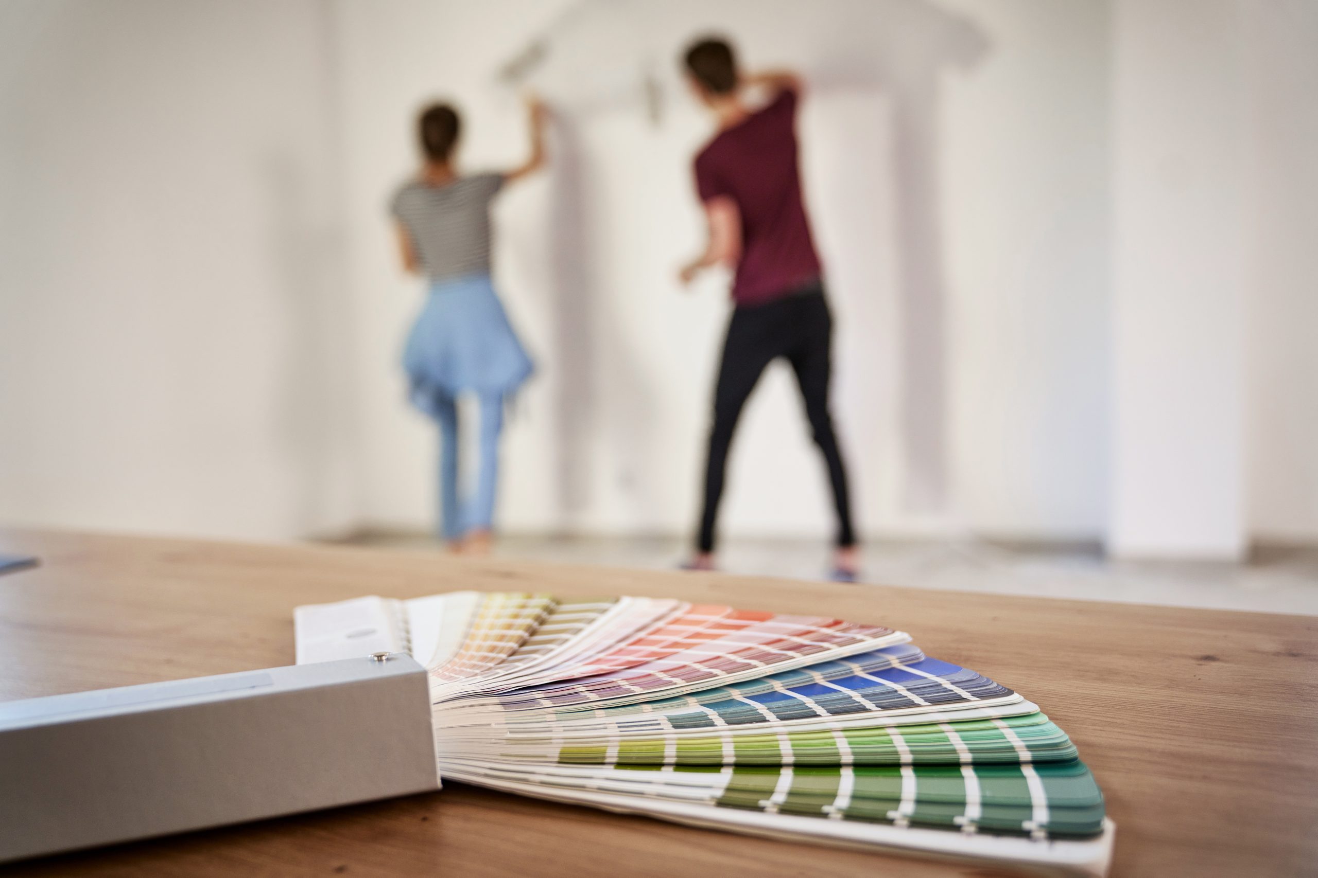 Blurred couple in the background painting wall in the house