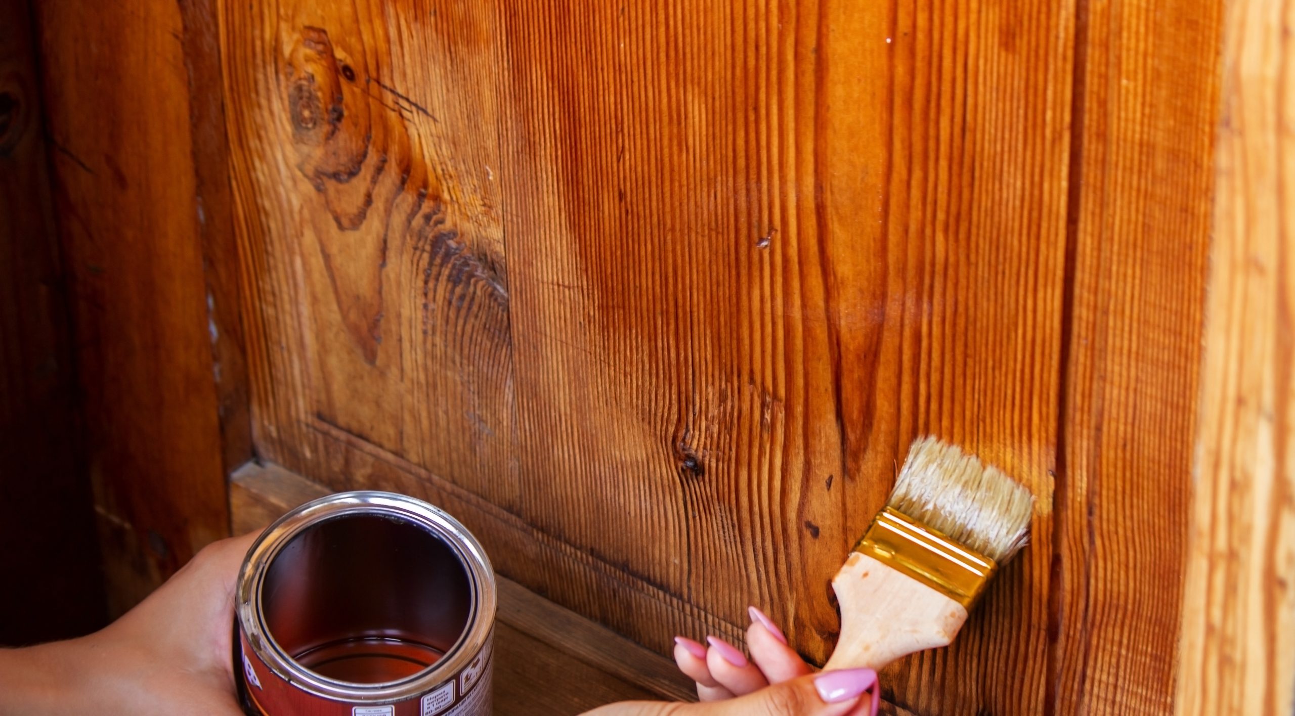 Beautiful young girl paints a wooden door. Summer work in the garden.